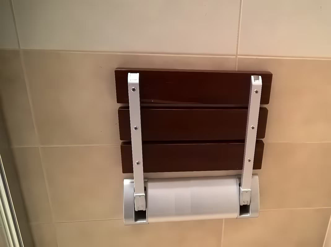 Sklopive sjedalo za tuš Multi u smeđoj izvedbi od masivnog drva Bulletwood s zidnim nosačem.