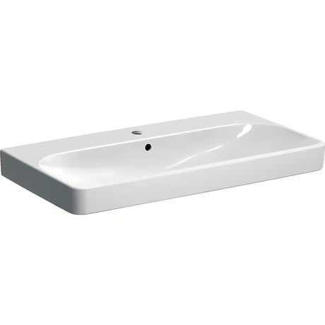 Bijeli viseći umivaonik Geberit Smyle Square 90x48 cm od sanitarne keramike s preljevom i otvorom pro za slavinu.