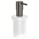 Dozator sapuna Grohe Essentials bez držača u izvedbi hard graphite, staklena posuda i metalni elementi.