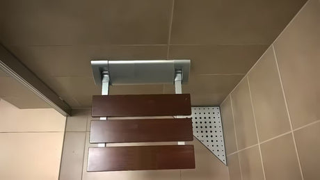 Sklopive sjedalo za tuš Multi u smeđoj izvedbi od masivnog drva Bulletwood s zidnim nosačem.